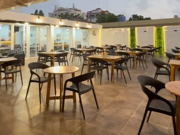 Terrasse de restaurant au crépuscule, tables en bois sous une pergola à claire-voie
